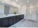 Main bathroom with double sinks, dark cabinets, and a glass-enclosed shower, offering a spa-like retreat at 3503 Luca Point Ave, Henderson, NV 89044