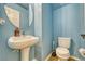 Cozy powder room features a pedestal sink, a modern toilet, and light blue walls, enhancing a clean and fresh look at 5179 Floralita St, Las Vegas, NV 89122