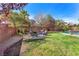 Lush backyard featuring a green lawn, mature trees, and an outdoor seating area with an umbrella at 5868 Revital Ct, Las Vegas, NV 89131