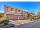 Two-story home with a brick driveway leading to a three-car garage, complemented by mature landscaping at 5868 Revital Ct, Las Vegas, NV 89131