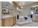 Bright bathroom featuring a soaking tub, dual vanities with stone counters and neutral tile flooring at 65 Luce Del Sole # 1, Henderson, NV 89011