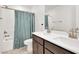 Well-lit bathroom featuring double vanity sinks, a large mirror and tub/shower combo with a blue curtain at 6618 Palm Branch St, North Las Vegas, NV 89086