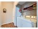 Efficient laundry room with a side-by-side washer and dryer, shelving, and wood-look flooring at 7835 Meandering Path Ave, Las Vegas, NV 89131