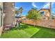 Beautiful backyard with an orange tree, artificial grass, and a view of neighboring homes at 9037 Wolf Dancer Ave, Las Vegas, NV 89143