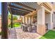 Relaxing covered patio featuring a stone brick floor, outdoor seating, and a well-manicured lawn at 9037 Wolf Dancer Ave, Las Vegas, NV 89143