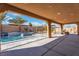 Covered patio overlooks sparkling pool, spa, with waterfall feature and palm trees at 9091 Becket Ranch Ct, Las Vegas, NV 89113