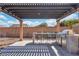 Outdoor kitchen beneath pergola featuring bar seating and a stainless steel grill at 9091 Becket Ranch Ct, Las Vegas, NV 89113