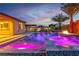 Inviting backyard pool and spa featuring fire feature, waterfall, colorful lighting, and a covered patio with outdoor dining at 9091 Becket Ranch Ct, Las Vegas, NV 89113