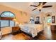 Bright bedroom featuring wood floors, an arched window, and a ceiling fan at 9532 Cliff View Way, Las Vegas, NV 89117