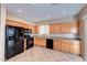 Bright kitchen with wood cabinetry, black appliances, tile floors, and a window over the sink at 10383 Gwynns Falls St, Las Vegas, NV 89183