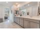 Bright bathroom featuring double sinks, neutral tile flooring, and grey cabinets and drawers at 10438 Skye Arroyo Ave, Las Vegas, NV 89166
