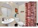 Compact half bathroom featuring a pedestal sink, toilet, decorative shower curtain and floating shelves at 2212 Barton Mill Ct, North Las Vegas, NV 89084