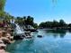 Scenic view of a cascading waterfall feature into a pristine lake surrounded by lush greenery and clear blue skies at 2212 Barton Mill Ct, North Las Vegas, NV 89084