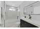 Bright bathroom featuring marble walls, a soaking tub with shower and a black vanity at 2402 El Cid Ct, Henderson, NV 89014