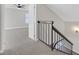 Hallway with carpet, a black metal banister, and a doorway to a bedroom with a ceiling fan at 2402 El Cid Ct, Henderson, NV 89014