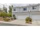 Desirable townhome features light gray exterior, a two-car garage, and charming landscaping for attractive curb appeal at 2405 Esteem Ridge Dr, Henderson, NV 89052