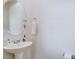Modern pedestal sink in half bathroom with a round mirror and a towel holder at 3524 Crotone Ave, Henderson, NV 89044