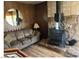 Living room featuring a wood burning stove, cozy couch, wood paneled walls, and wood laminate flooring at 424 Jefferson Blvd, Henderson, NV 89011