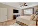 A cozy bedroom featuring a ceiling fan, wood floors, large window, and a wall-mounted TV for ultimate relaxation at 5741 Shadow Bend Dr, Las Vegas, NV 89135