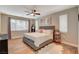 Cozy bedroom with a tufted headboard, wood-look flooring, and bright windows at 5741 Shadow Bend Dr, Las Vegas, NV 89135