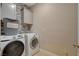Functional laundry room with modern washer and dryer, storage cabinet, and tiled backsplash at 5741 Shadow Bend Dr, Las Vegas, NV 89135
