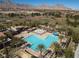 Aerial shot of a resort-style pool area with palm trees, sun loungers, and mountain views at 575 Lacabana Beach Dr, Las Vegas, NV 89138