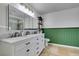 Well-lit bathroom with a marble countertop, white cabinets, and a dark green accent wall at 6686 Enchanted Cove Ct, Las Vegas, NV 89139