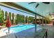Inviting backyard pool with a poolside bar, a covered seating area and tall privacy hedges at 6686 Enchanted Cove Ct, Las Vegas, NV 89139