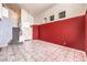 Spacious living room with tile flooring and contrasting red accent wall, leading to an open staircase at 7267 Sequoia Springs Dr, Las Vegas, NV 89147