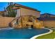 Backyard oasis with a rock slide, waterfall feature, pristine pool, and lush artificial turf at 7370 Glowing Point St, North Las Vegas, NV 89084