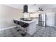 Modern kitchen with breakfast bar, sleek appliances, and unique black and white patterned tile flooring at 7817 Aplin Ave, Las Vegas, NV 89145