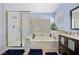 Bright bathroom featuring a soaking tub, glass-enclosed shower, and dark wood vanity at 820 Sandhill Sage St, Henderson, NV 89052