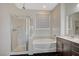 Well-lit bathroom featuring a walk-in shower, soaking tub, and dark wood vanity at 8754 Moon Crater Ave, Las Vegas, NV 89178