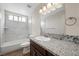 Bright bathroom features granite countertops, framed mirror, and tiled shower-over-tub at 8912 Dio Guardi Dr, Las Vegas, NV 89117
