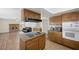 Well-lit kitchen featuring wood cabinets, stainless steel appliances, and an island cooktop, next to living room at 8912 Dio Guardi Dr, Las Vegas, NV 89117