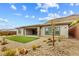Desert landscaping in the backyard with a grass patch and covered patio with sliding glass doors at 10016 Copper Edge Rd, Las Vegas, NV 89148