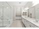 Bright bathroom featuring double sinks, white cabinetry, quartz countertops, and a glass enclosed shower and tub at 10016 Copper Edge Rd, Las Vegas, NV 89148