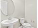 Cozy powder room featuring a pedestal sink, toilet, and round mirror at 10016 Copper Edge Rd, Las Vegas, NV 89148