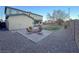 Exterior view of a backyard featuring a fire pit, gravel, grass, covered patio and exterior of home at 10105 Prattville Ave, Las Vegas, NV 89148