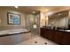 Bright bathroom showcasing a soaking tub, shower, and a double sink vanity with dark wood cabinets and large mirror at 135 E Harmon Ave # 307, Las Vegas, NV 89109