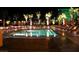 Night view of an illuminated outdoor pool area with lounge chairs and palm trees at 135 E Harmon Ave # 307, Las Vegas, NV 89109