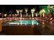 Inviting swimming pool illuminated at night, surrounded by lounge chairs and palm trees at 135 E Harmon Ave # 307, Las Vegas, NV 89109