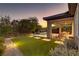 A well-manicured backyard at dusk with lush greenery and a covered patio at 15 Reflection Bay Dr, Henderson, NV 89011