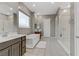 Modern bathroom with dual sinks, a soaking tub, a glass-enclosed shower, and neutral-colored tile flooring at 15 Reflection Bay Dr, Henderson, NV 89011