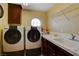 Laundry room with a round window, countertop space, sink, and modern washer and dryer units at 1883 Nature Park Dr, North Las Vegas, NV 89084