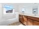 Bright bathroom with a soaking tub, double vanity with wood cabinets and a window at 2300 Trasimeno Pl, Henderson, NV 89044