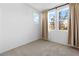 Bright bedroom with neutral carpet, three large windows, and flowing beige curtains at 2300 Trasimeno Pl, Henderson, NV 89044