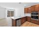 Open kitchen with warm cabinets, stainless steel dishwasher, oven, and quartz countertops at 2300 Trasimeno Pl, Henderson, NV 89044