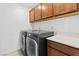 A clean laundry room features washer and dryer, upper cabinets, and counter space at 2300 Trasimeno Pl, Henderson, NV 89044