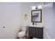 Cozy half bathroom features a dark gray vanity, toilet, and modern mirror with wall art at 3057 Downing Pl, Las Vegas, NV 89121